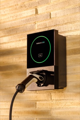 A Humax MX7 EV charger with a green LED ring, mounted on a stone wall