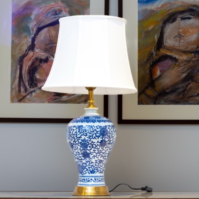 A blue-and-white patterned ceramic lamp in front of artwork — Yasmeen Artisan